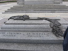 Une tombe en granite gravée Tom du Soldat inconnu sur le côté; une sculpture à relief en bronze se trouve au sommet du sarcophage