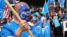 Demonstrators dressed in light blue and wearing blue facepaint, holding blue flags with white crescent