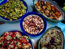 La phtographie couleur montre un assortiment de cinq bols et plats garnis de hors-d'œuvre variés : tomate, olives, courgettes, poivrons... Tous les plats ne sont pas identifiables.