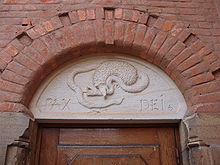 un hérisson mordant un serpent sculpté au fronton d'un bâtiment