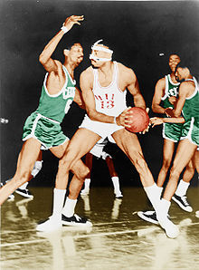 Bill Russell, le numéro 6 des Celtics de Boston avec son maillot vert, défend sur Wilt Chamberlain qui tient le ballon de basket-ball dans ses mains.