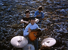 Trois des Beatles l'un derrière l'autre, avec leurs instruments.