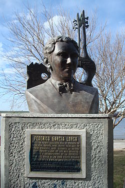 Buste en bronze de Garcia Lorca posé sur un socle portant une plaque gravée de son nom et d'une biographie succincte. Le buste est surmonté, à l'arrière, d'une guitare et d'un objet qui pourrait être une page de livre déchirée, percés d'un trou béant symbolisant la mort du poète. L'ensemble est installé dans un parc.