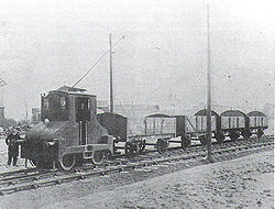 Le conducteur se tient à côté de la locomotive électrique remorquant quatre wagons de charbon