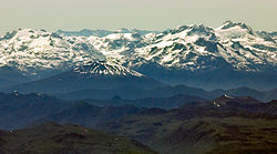 Vue de l'Hornopirén (cône enneigé à gauche) et de l'Apagado (couronné par un cratère à droite) au premier plan avec les Andes au dernier plan.