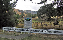 Vue du panneau au départ du sentier menant à la colline visible au dernier plan.
