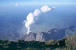 Le dôme de lave fumant du Santiaguito vu depuis le sommet du Santa María, en arrière plan la plaine côtière bordant l'océan Pacifique.