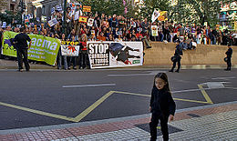  Au premier plan une petite fille, et en arrière-plan des manifestants tenant diverses banderolles.