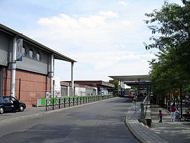 Entrée de la gare au niveau de la voie de circulation des bus menant à la gare routière au 2e plan.