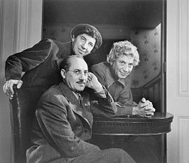 Harpo Marx, debout, à droite. À gauche, Chico Marx ; assis, Groucho Marx.