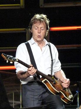 Paul McCartney sur scène, qui joue sur sa guitare basse.