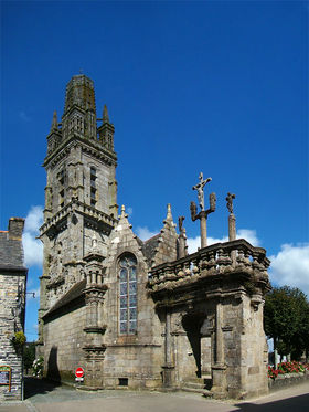 Vue de l'église Notre-Dame et de son enclos paroissial. À droite, l'arc de triomphe qui sépare la vie profane de l'espace religieux. À gauche, le clocher, tronqué en 1809 par la foudre qui l'a amputé de 18 mètres.