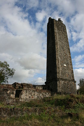 Vue d'une cheminée d'usine en ruines sur le domaine de Villèle.