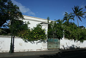 Aperçu, derrière la végétation, de la façade de la maison de la Banque de La Réunion