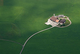 photo aérienne d'une exploitation agricole composé de 3 bâtiments, la photo donne l'impression que l'exploitation est une île au milieu d'une mer verte
