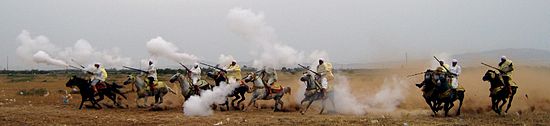 Fantasia exécutée à Bni Drir, Maroc, par un groupe de cavaliers, photographiées au moment du tir de la salve de fusils.